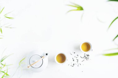 Çay ve çaydanlık iki beyaz bardak beyaz arka plan üzerinde yeşil yaprakları ile çevrili