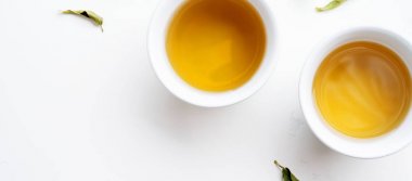 Beyaz arka plan üzerinde yeşil çay kuru yaprakları ile çay iki beyaz bardak