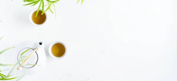 Dva Bílé Šálky Čaje Čajového Hrnce Obklopené Zelenými Listy Bílém — Stock fotografie