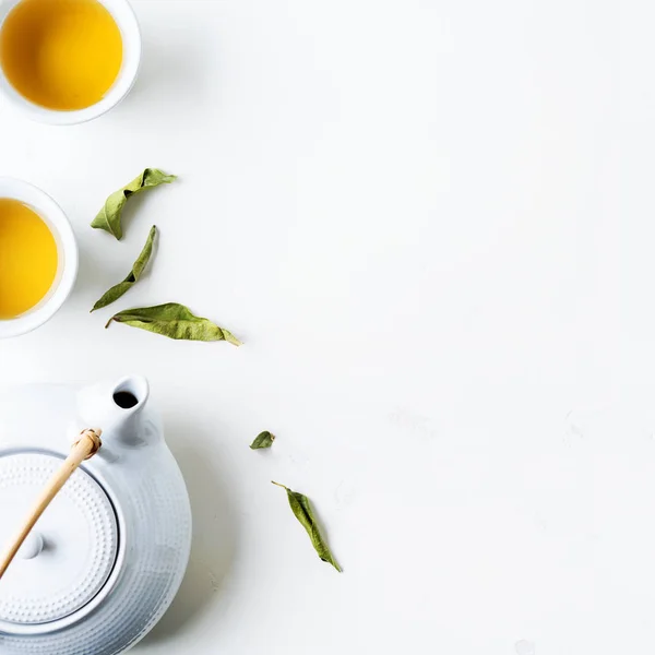 Дві Білі Чашки Чаю Чайника Оточенні Зеленого Листя Білому Тлі — стокове фото