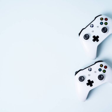 Pastel mavi zemin üzerine iki Xbox gamepads denetleyicisi oyun çubukları 