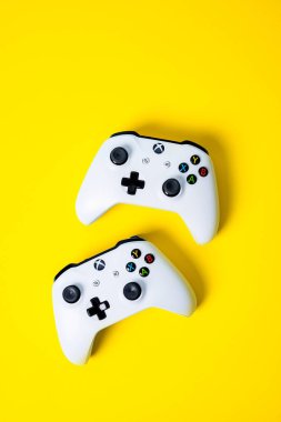 Parlak sarı arka planda iki Xbox gamepad denetleyicijoysticks 