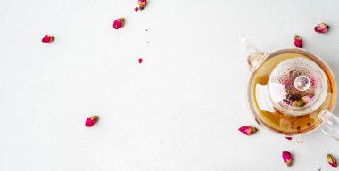 Kurutulmuş pembe ile bitkisel çay şeffaf çaydanlık gri arka planda tomurcuk gül