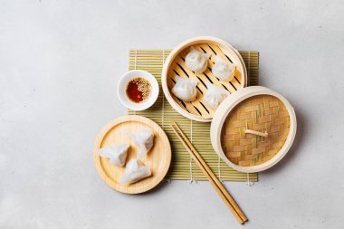 Geleneksel Çince köfte Dim toplamları Har Gow sos ve yemek çubukları ile bambu gemi içinde ışık arka plan üzerinde buğulama