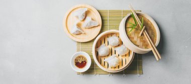 Geleneksel Çince köfte Dim toplamları Har Gow sos ve yemek çubukları ile bambu gemi içinde ışık arka plan üzerinde buğulama