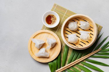 Geleneksel Çince köfte Dim toplamları Har Gow sos ve yemek çubukları ile bambu gemi içinde ışık arka plan üzerinde buğulama