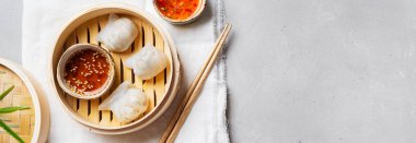 Geleneksel Çince köfte Dim toplamları Har Gow sos ve yemek çubukları ile bambu gemi içinde ışık arka plan üzerinde buğulama