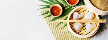 Geleneksel Çince köfte Dim toplamları Har Gow sos ve yemek çubukları ile bambu gemi içinde ışık arka plan üzerinde buğulama