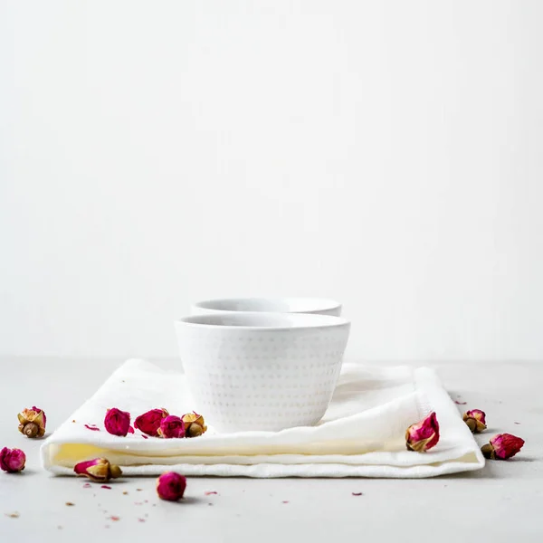 两个白色陶瓷的草药茶与干燥的粉红色玫瑰芽在灰色背景 — 图库照片