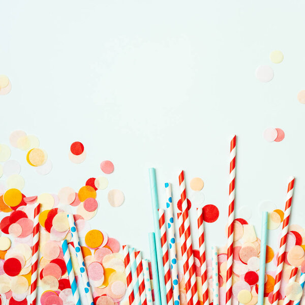 Куча красных и синих соломинок на фоне пастели с красочными конфетти
