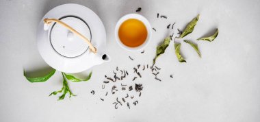 Yeşil taş arka plan üzerinde yeşil çay kuru yaprakları ile çevrili çay ve çaydanlık Seramik fincan