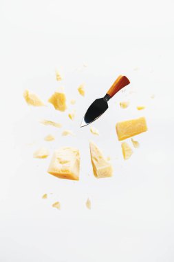 Parmesan peyniri beyaz arka plan üzerinde kırıntıları ve peynir bıçağı ile uçan