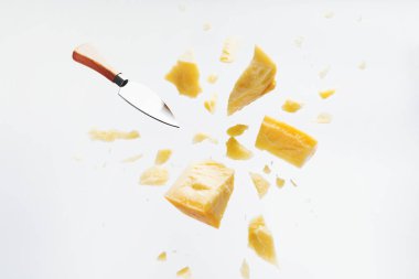 Parmesan peyniri beyaz arka plan üzerinde kırıntıları ve peynir bıçağı ile uçan