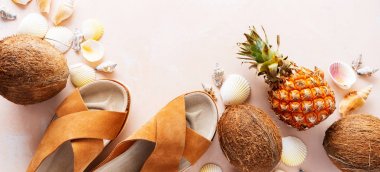 Pembe pastel arka plan üzerinde deri trendy parmak arası terlik, kabuklar ve tropikal meyvelerüst görünümü