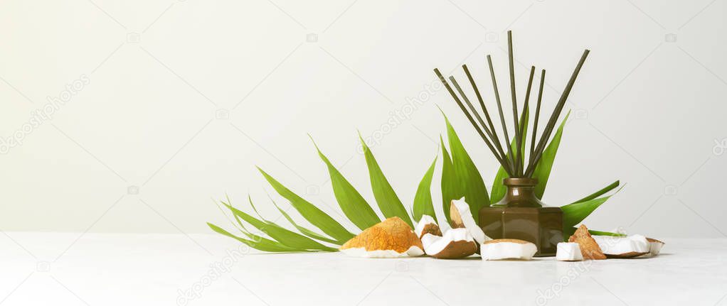 Aroma reed diffuser bottle home fragrance with rattan sticks and fresh coconut pieces on white background 