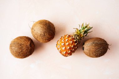 Pembe pastel arka plan üzerinde kabuk ve ananas taze tropikal hindistan cevizi