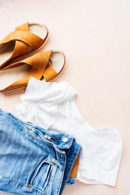 Pembe pastel arka plan üzerinde temel beyaz t-shirt, kot şort ve trendy deri sandalet