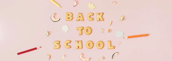 五颜六色的背景与文字回学校的饼干在粉红色的粉彩背景 — 图库照片