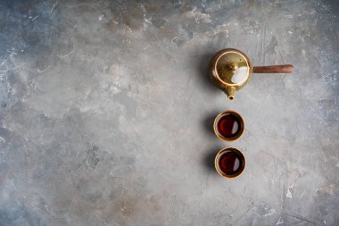 Gri beton arka plan üzerinde iki çay fincanı ile yan kolu ile geleneksel kil Japon çaydanlık kyusu üst görünümü