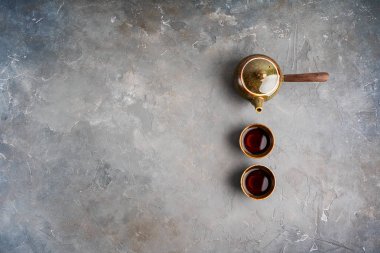 Gri beton arka plan üzerinde iki çay fincanı ile yan kolu ile geleneksel kil Japon çaydanlık kyusu üst görünümü