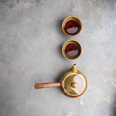 Gri beton arka plan üzerinde iki çay fincanı ile yan kolu ile geleneksel kil Japon çaydanlık kyusu üst görünümü