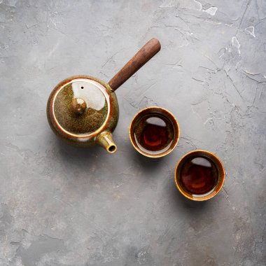 Gri beton arka plan üzerinde iki çay fincanı ile yan kolu ile geleneksel kil Japon çaydanlık kyusu üst görünümü