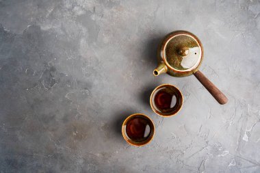 Gri beton arka plan üzerinde iki çay fincanı ile yan kolu ile geleneksel kil Japon çaydanlık kyusu üst görünümü