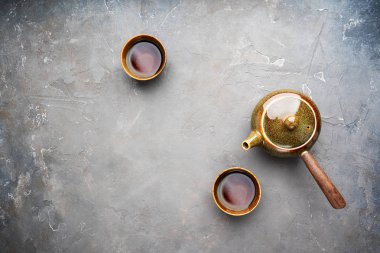 Gri beton arka plan üzerinde iki çay fincanı ile yan kolu ile geleneksel kil Japon çaydanlık kyusu üst görünümü