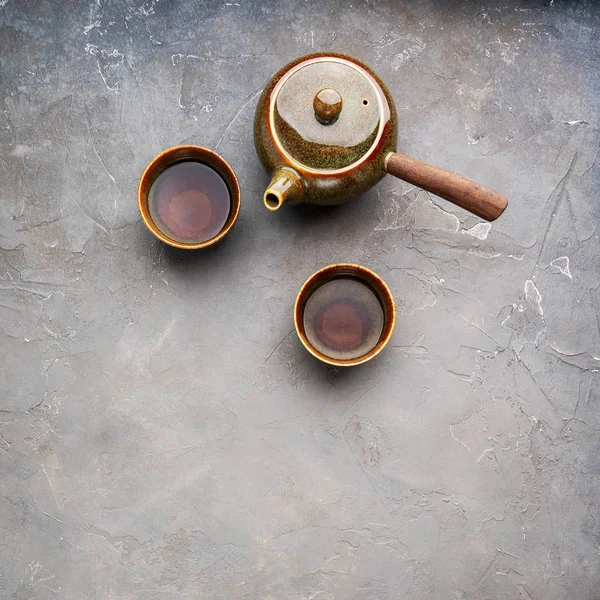 传统粘土日本茶壶的顶视图 侧手柄与灰色混凝土背景上的两个茶杯 — 图库照片