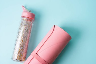 Turkuaz mavisi arka planda pembe spor paspas ve su şişesi