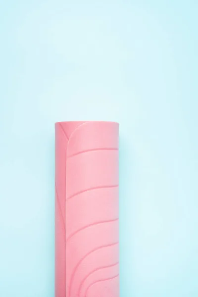 青いパステルの背景にピンクのロールスポーツマット — ストック写真