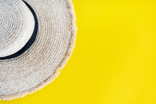 Close view of stylish straw hat over yellow background 