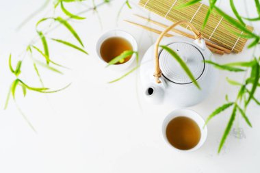 Asya yeşil yaprakları ile beyaz zemin üzerine yeşil çay, bardak ve çaydanlık ayarla 