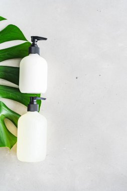 Yeşil yaprakları ile gri beton arka plan üzerinde ambalaj için şişe Kozmetik seti