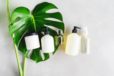 Yeşil yaprakları ile gri beton arka plan üzerinde ambalaj için şişe Kozmetik seti