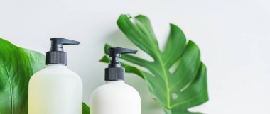 Yeşil yaprakları ile gri beton arka plan üzerinde ambalaj için şişe Kozmetik seti