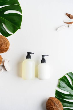 Yeşil yaprakları ve hindistan cevizi ile gri beton arka plan üzerinde ambalaj için şişe Kozmetik seti 