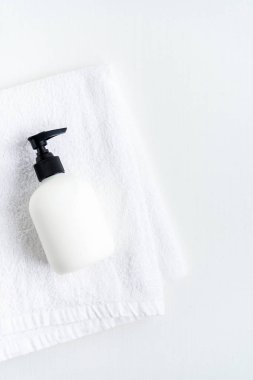 Hafif arka planda beyaz kabarık havlu üzerinde dispenser şişe üst görünümü