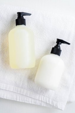 Close view of bottles lying on white fluffy towel over white background clipart