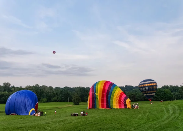 Biella, Italy, June 10, 2018 -Three hot air balloons being anchored and deflated after the flight, and one balloon in the sky at spring festival, June Pollone dal Cielo, Biella