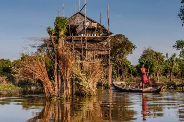 Tonle Sap Gölü' ndeki bir balıkçı köyünde evin yakınında bir teknede bir balıkçı, Kamboçya