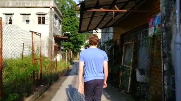 放棄された村を歩くティーンエイジャーのバックビュー — ストック動画