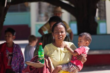Bago, Myanmar - 22 Aralık 2011: Birmanyalı bir kadın bir çocuk ve bir şişe meşrubat tutuyor