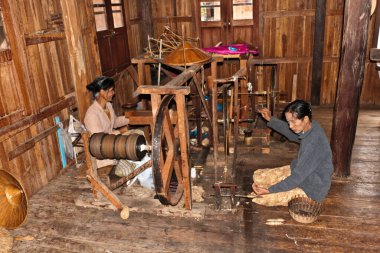 Birmanyalı kadınlar Inle Gölü, Myanmar 'daki bir köy evinde el dokuma tezgahında çalışıyor.