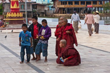 Çocuk ve Budist keşişler Phaung Daw Oo Pagoda, Taunggyi, Myanmar yakınlarında güvercinleri besliyor.