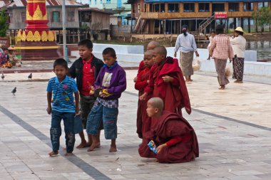 Children and Buddhist child monks feeding pigeons near the Phaung Daw Oo Pagoda, Taunggyi, Myanmar clipart