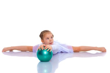 Küçük kız spor yapmak için büyük bir top üzerinde egzersiz yapıyor..