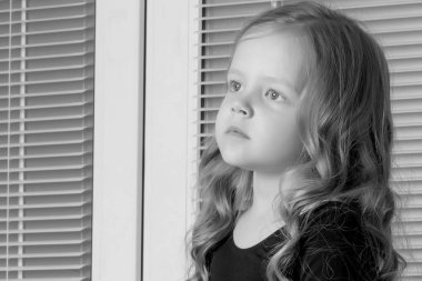 Küçük bir kız pencerenin arka plan üzerine oturuyor 