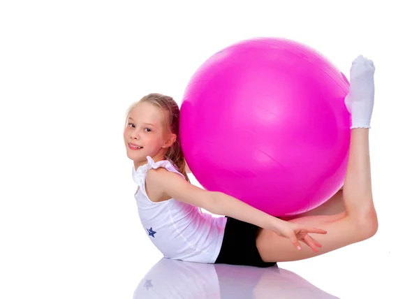 Kleines Mädchen macht Übungen auf einem großen Ball für Fitness. — Stockfoto