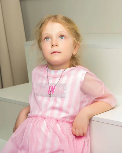 Schöne kleine Mädchen sitzt auf der weißen Treppe. — Stockfoto